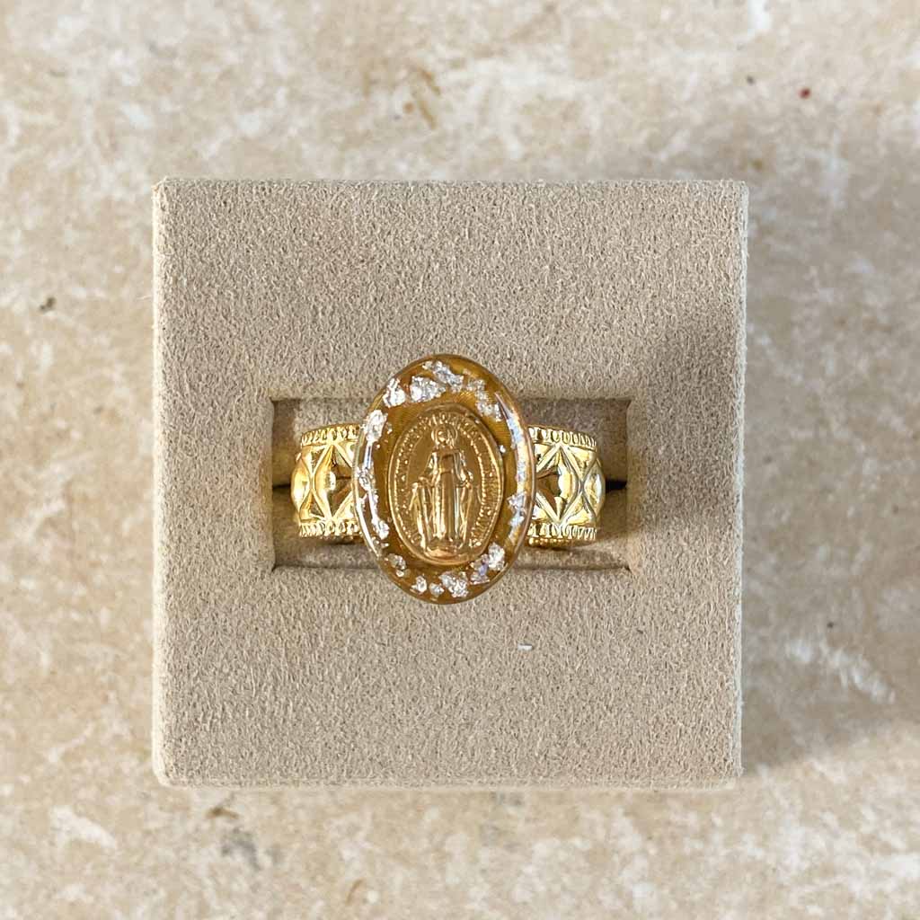 Bague médaille miraculeuse Fleur Nabert créations en acier doré avec couronne de feuilles d'argent sur fond beige