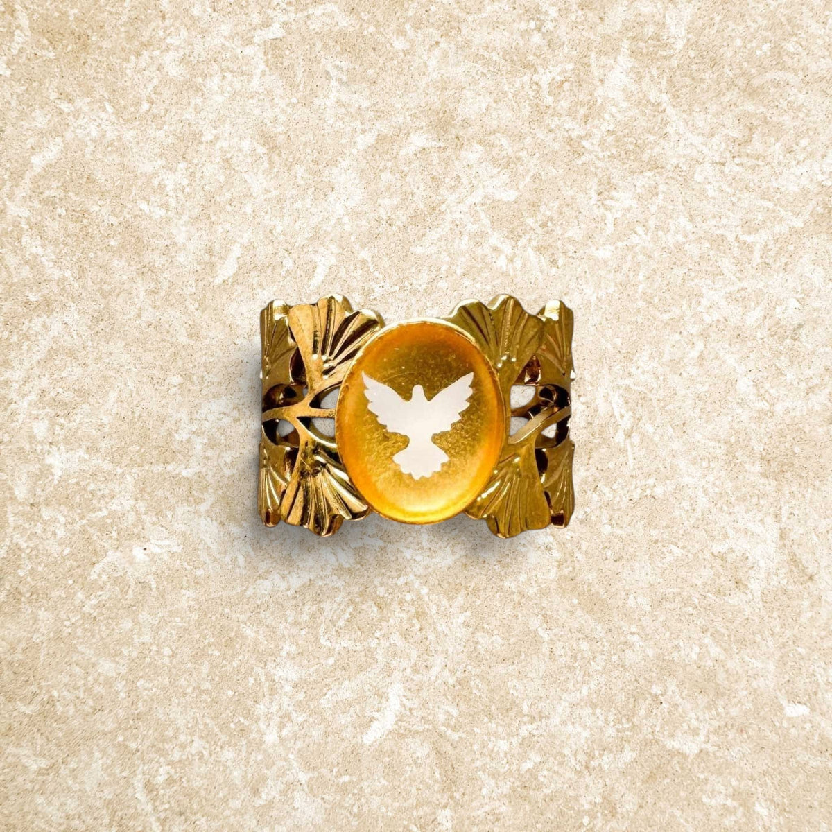 Gold-toned steel ring from Spiritus Fleur Nabert Creations featuring a dove, amber resin, and ginkgo leaf details