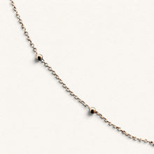 Charger l'image dans la galerie, Chaîne Sainte Elisabeth Fleur Nabert créations en argent massif plaqué or avec perles dorées sur fond bleu

