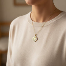 Charger l'image dans la galerie, Médaille Fleur Nabert créations en forme de colombe blanche sur fond doré portée en collier par une jeune fille
